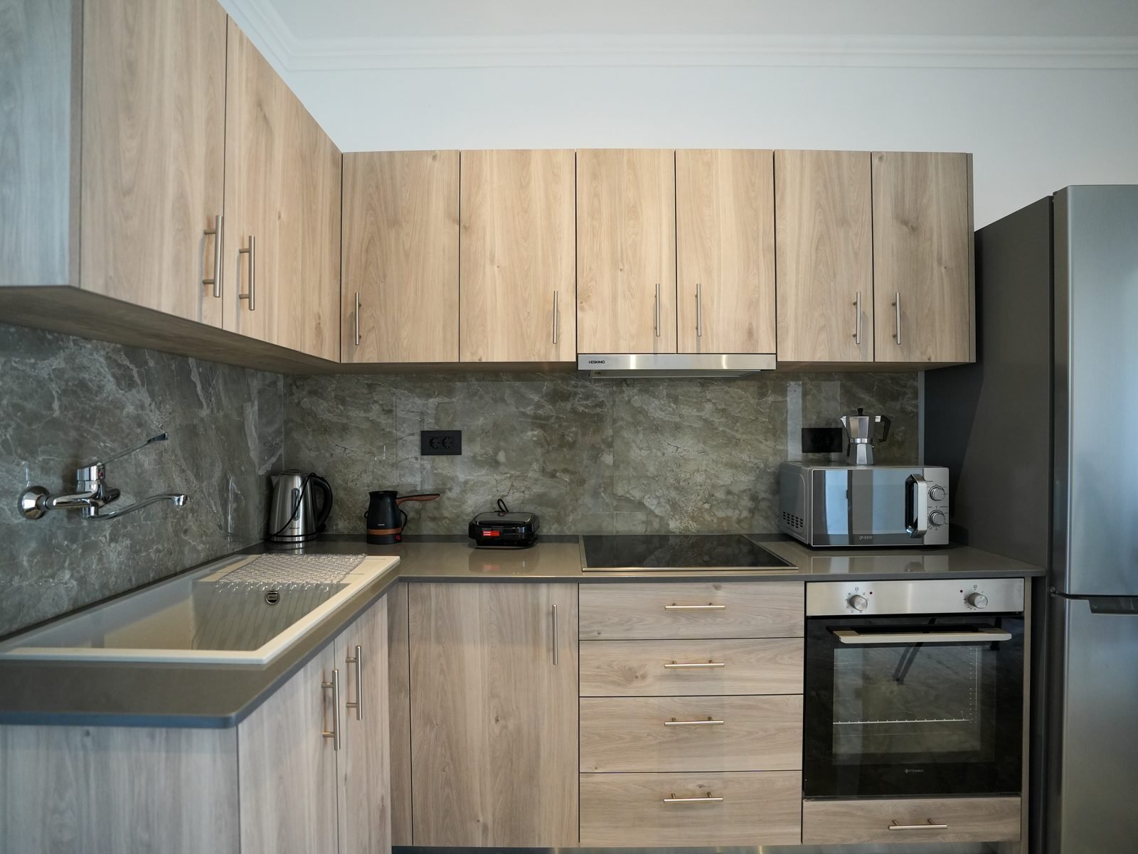 Kitchen with oven, hob, kettle, microwave and marble splashback